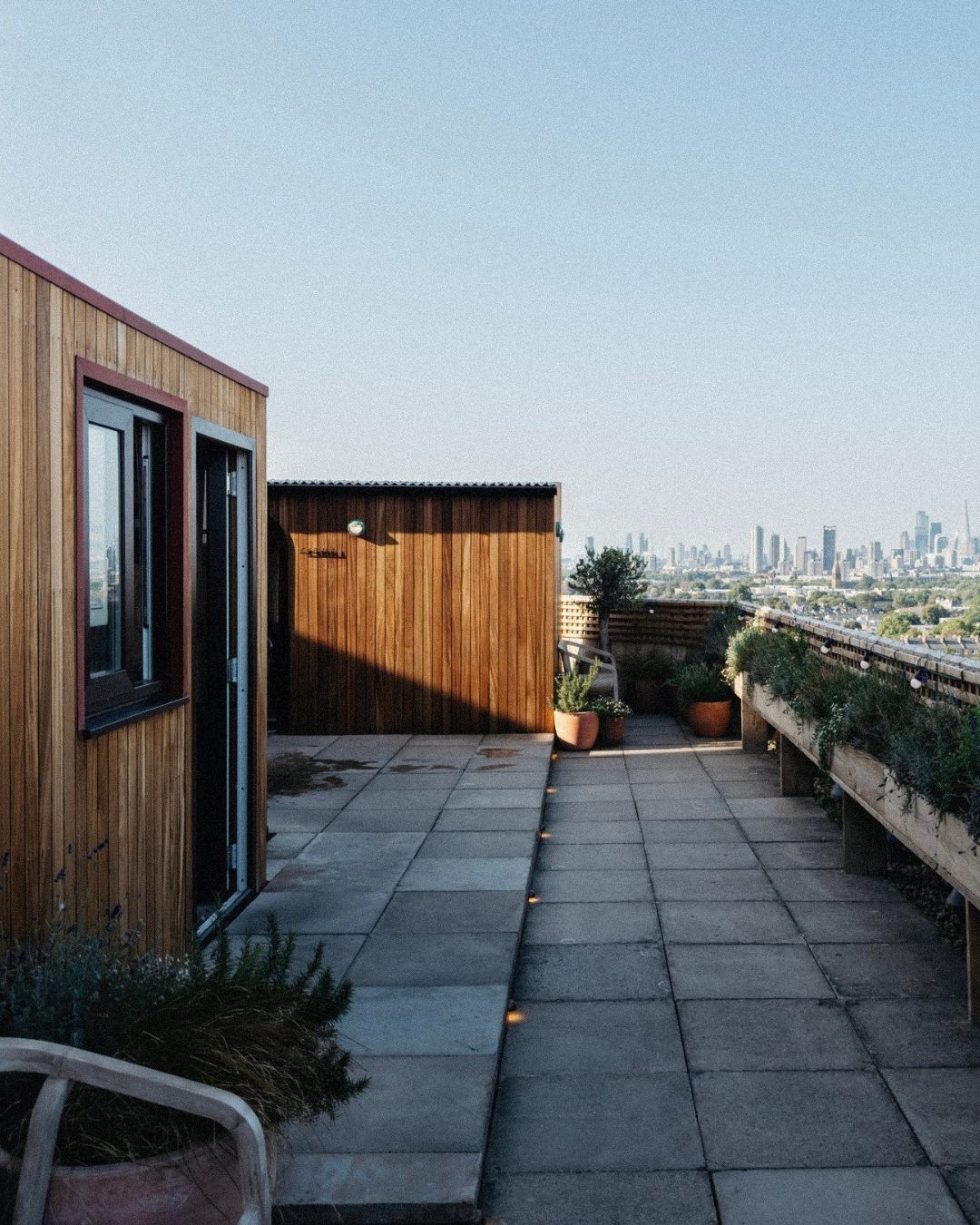 Timber sauna cabins on a London rooftop, looking towards the City skyline