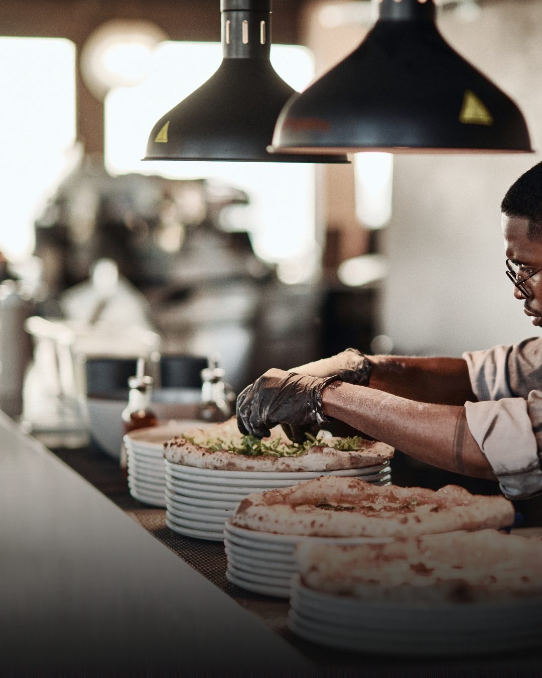 A chef finishing pizzas at the pass at The Birds Nest